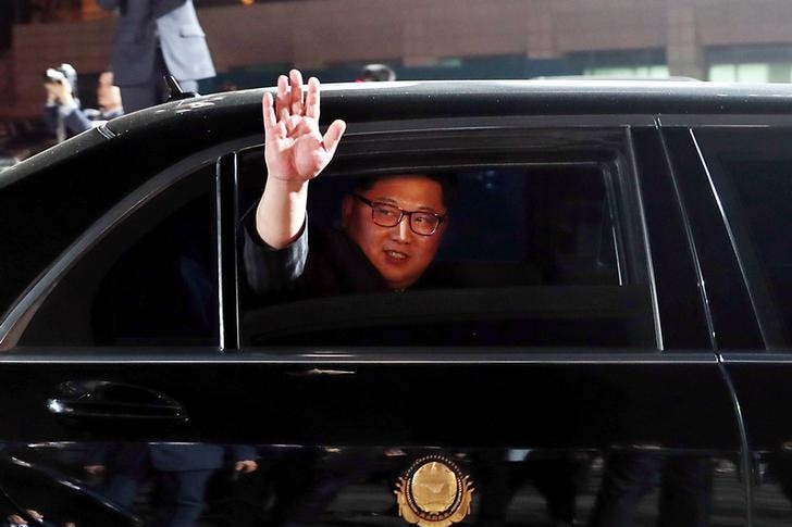 Kim Jong-un waves and smiles from the window of a car
