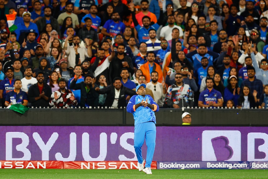 Suryakumar Yadav takes a catch with a packed stand behind him watching on