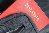 A Malaysian passport hanging out of a small bag