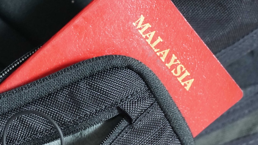 A Malaysian passport hanging out of a small bag