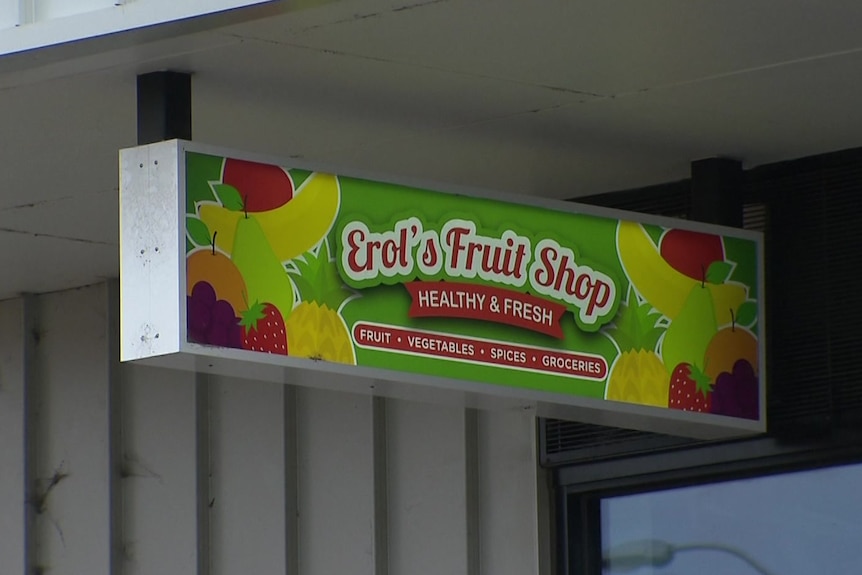 A bright green sign decorated with pictures of colourful fruit reads "Erol's Fruit Shop".