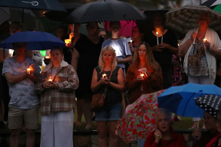About 10 people photographed at a night time vigil for stabbing victim Emma Lovell, with candle light showing their faces.
