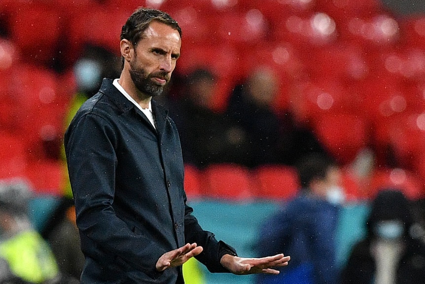 Gareth Southgate gestures with his hands low, palms parallel to the ground 