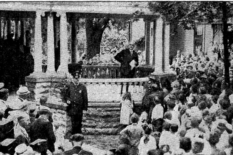 A black and white photo of Warren G Harding speaking from his porch to a crowd