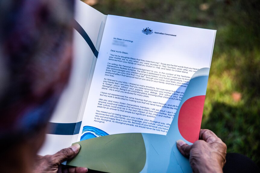 A woman holds a letter with the Australian Government header.