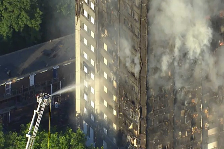 Firefighters spray water on smouldering Grenfell Tower