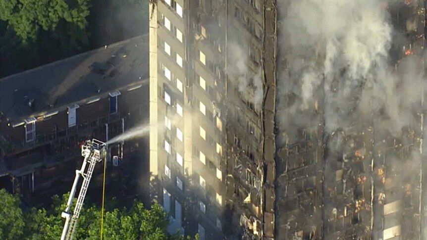 Firefighters spray water on smouldering Grenfell Tower