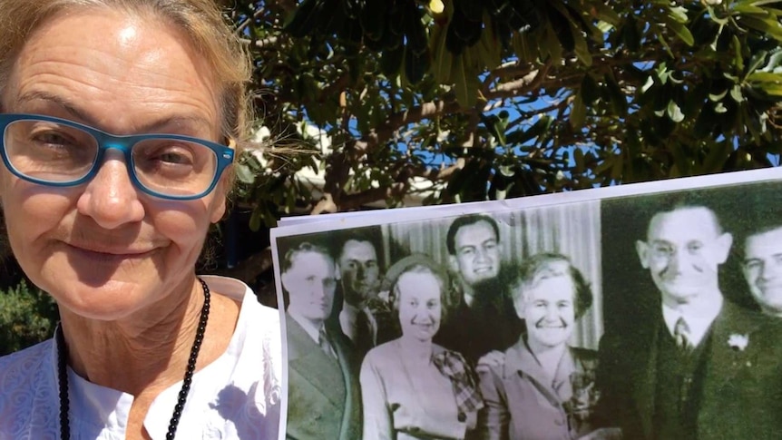 Sally Malone holds a black and white photo of her grandfather and father, his brothers and wives