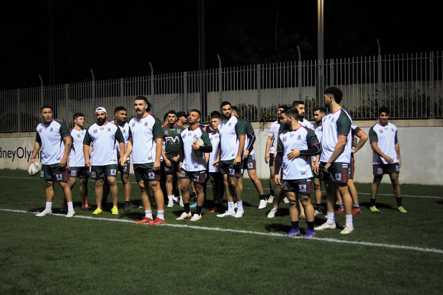 A group of rugby players stand on a football field.