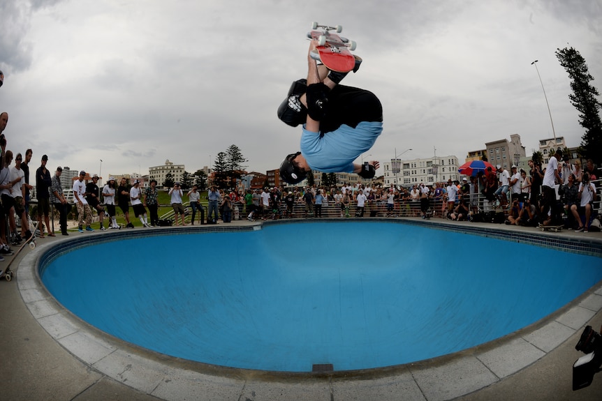 A skateboarder in the air as he practices in a skate bowl in Sydney.