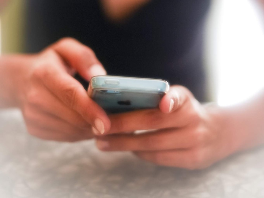 A woman looks at her iPhone.