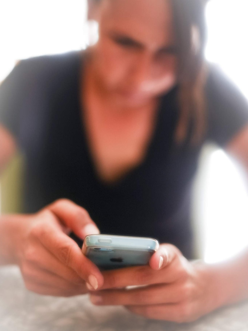 A woman looks at her iPhone.