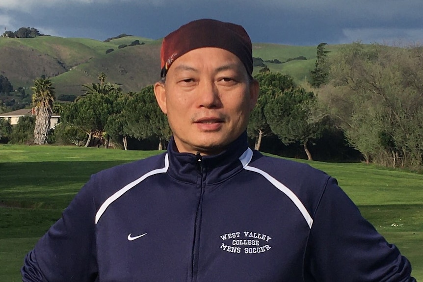 A photo of a man in running gear with his hands on his hips in front of a mountain.