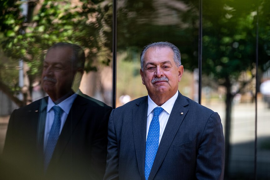 Andrew Liveris stands next to window. 