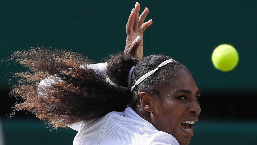 Serena Williams focuses on a shot with her mouth open and hand above her head.