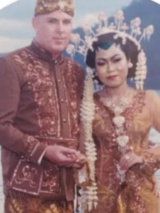 A Caucasian man standing next to an Indonesian woman. Both wearing traditional Javanese attire.