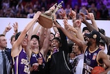 A mens professional basketball team celebrate with a trophy.