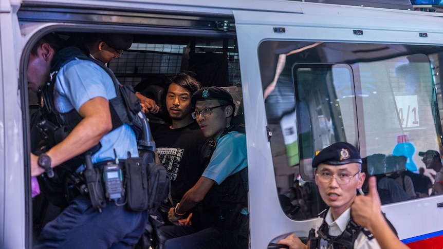 Activist Leo Tang is taken away by police in a van.