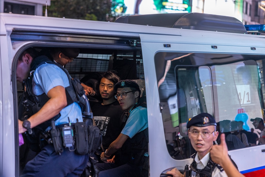 Activist Leo Tang is taken away by police in a van.