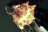 A structure on an island is bombed from the air -- there is a large fiery explosion.