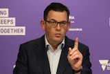 Daniel Andrews stands at a podium at a press conference.