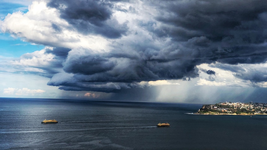 Ferries on the water as dark thunderstorm clouds loom overhead.