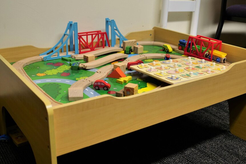 A wooden childs table with toys on it.