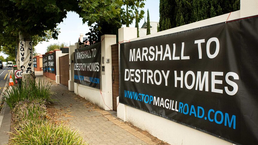 Several house fences have a sign saying Marshall to Destroy Homes hung on their frontage.