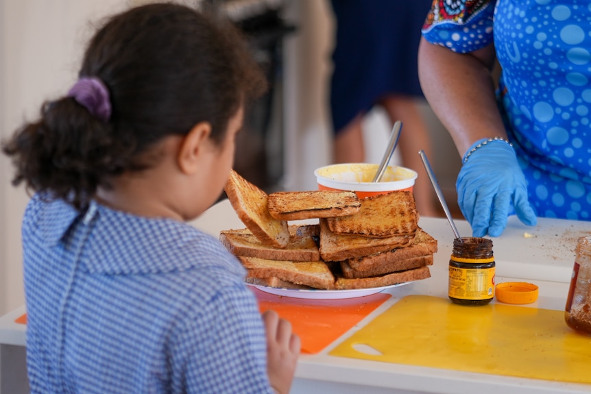 A primary school student receives a piece of toast with jam. 
