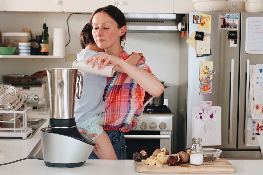Recipe writer Heidi Sze makes a banana and passionfruit smoothie while carrying her young son. 