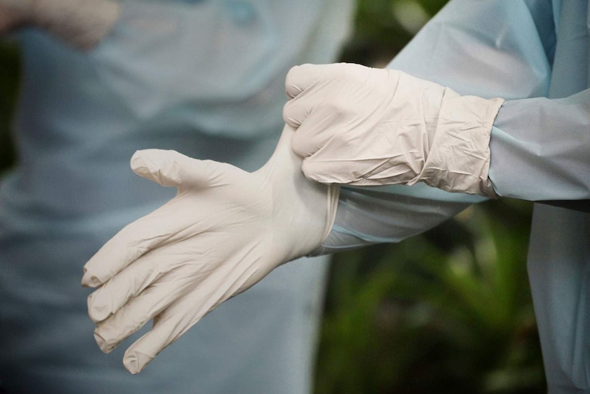 Close-up of Queensland Ambulance Service (QAS) paramedic putting on gloves