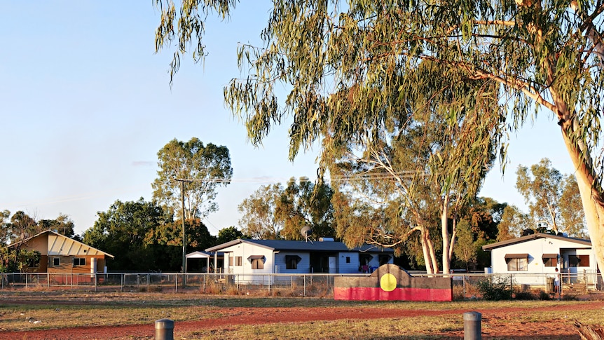 A park area in a rural hamlet surrounded by gum trees and red earth.