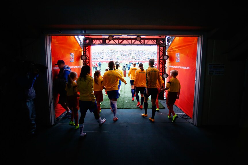 A group of footballers walk out onto the field.