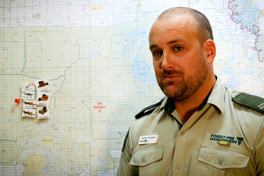 Man in green uniform standing in front of a map of the Mallee