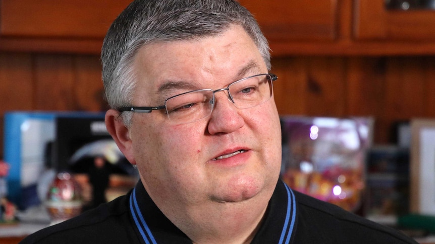 Headshot of a grey-haired man in glasses with tears in his eyes.