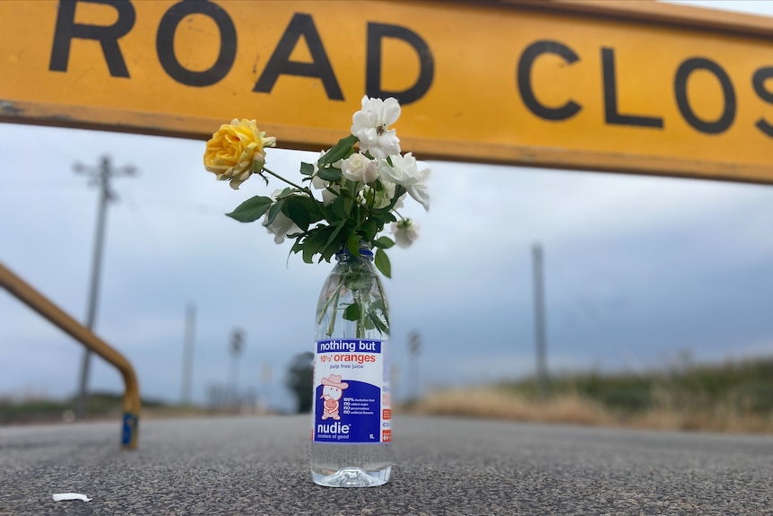 A bunch of flowers in front of a road closed sign