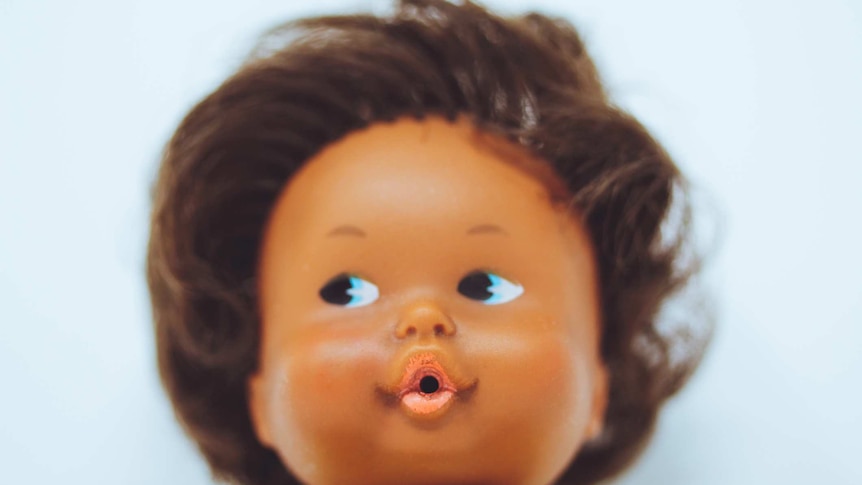 A close-up of a black doll with pouted lips and blue eyes