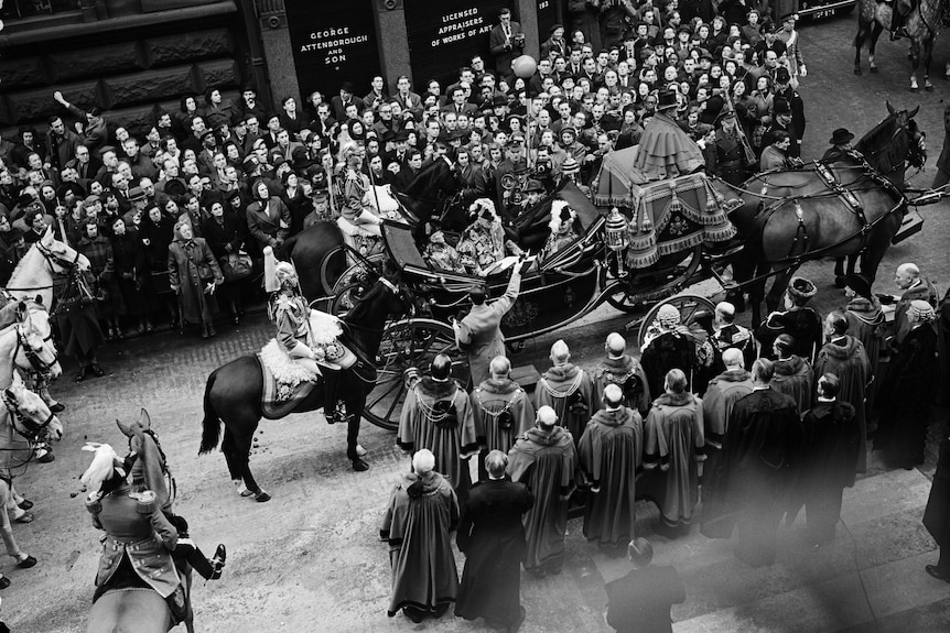 A black and white photo of crowds surrounding a horse-drawn carraige.