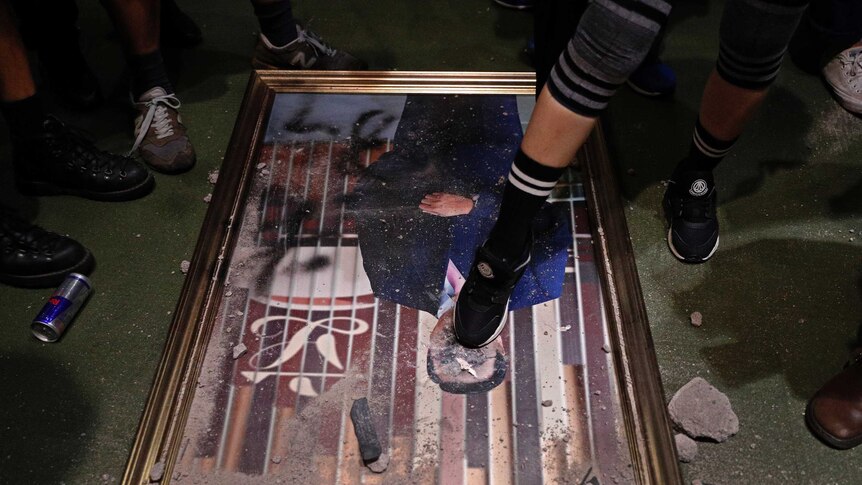 A damaged portrait of a former legislative leader lies on the ground