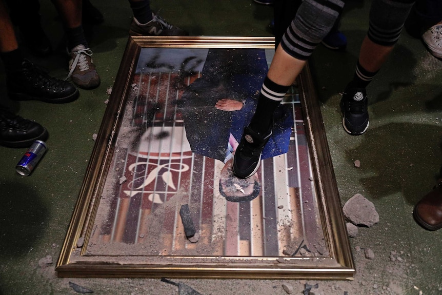 A damaged portrait of a former legislative leader lies on the ground