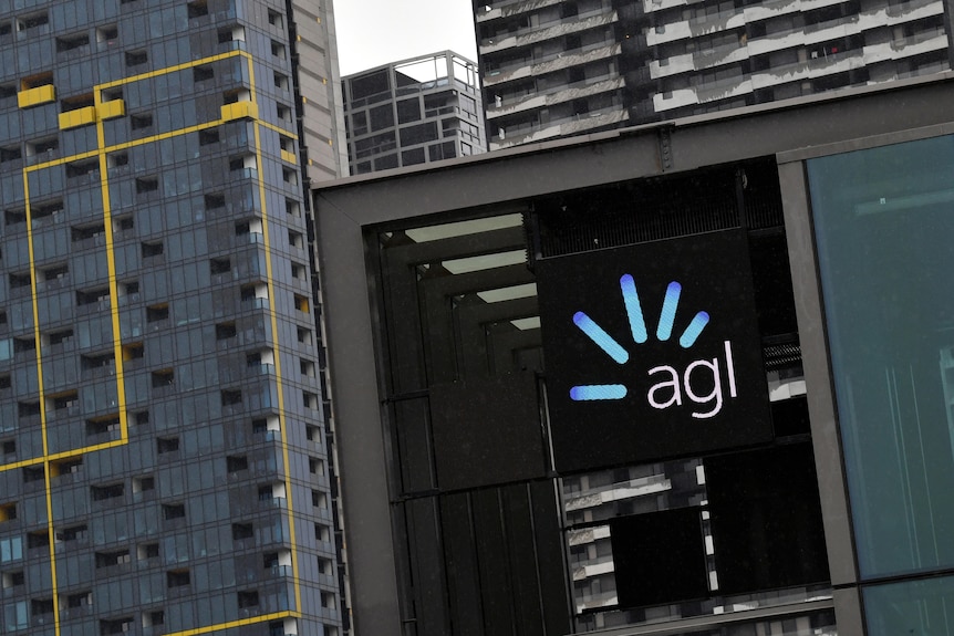 An office building with the AGL logo showing, with a backdrop of other sky-high office buildings on a grey day.