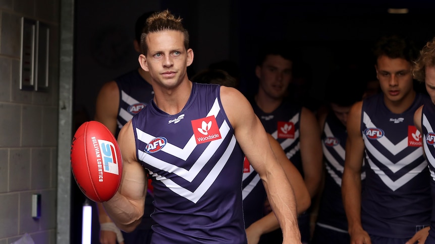 Nat Fyfe walks onto an AFL field, leading his teammates