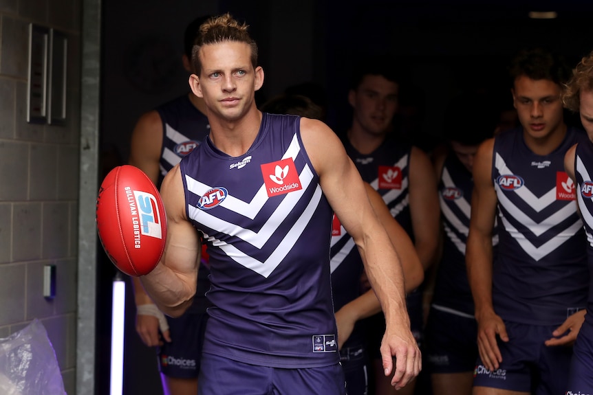 Nat Fyfe walks onto an AFL field, leading his teammates