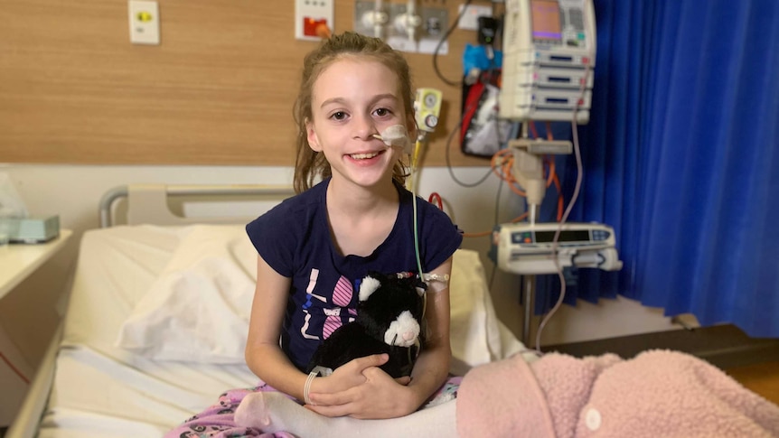 An 8-year-old sitting up in a hospital bed smiling