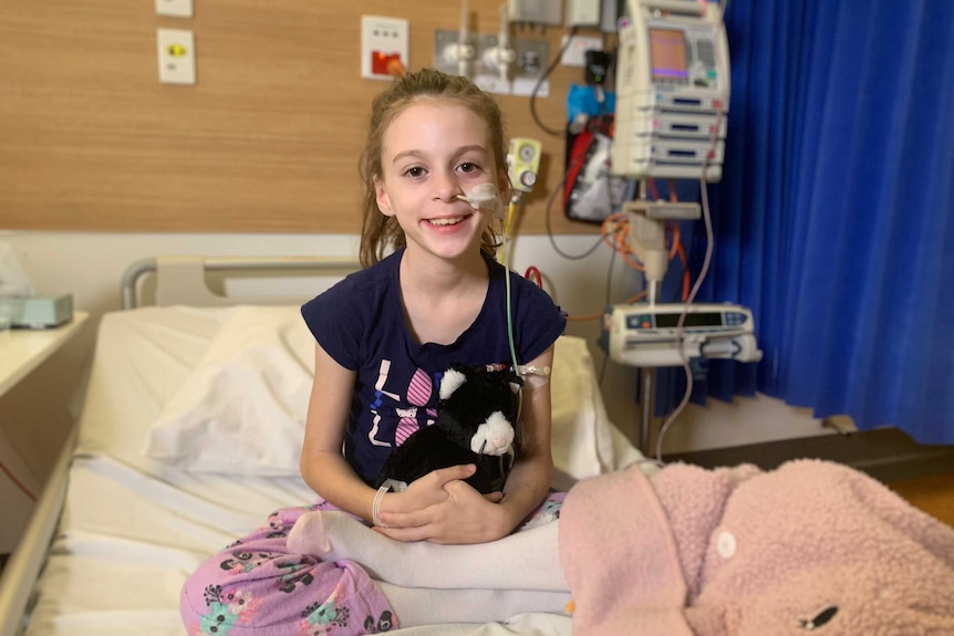 An 8-year-old sitting up in a hospital bed smiling