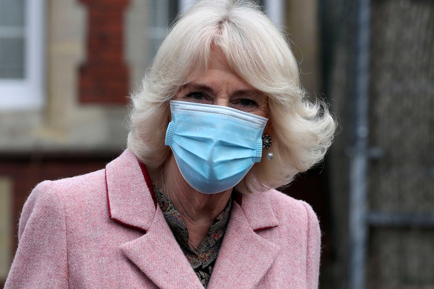 The Duchess of Cornwall wears a face mask and an overcoat.