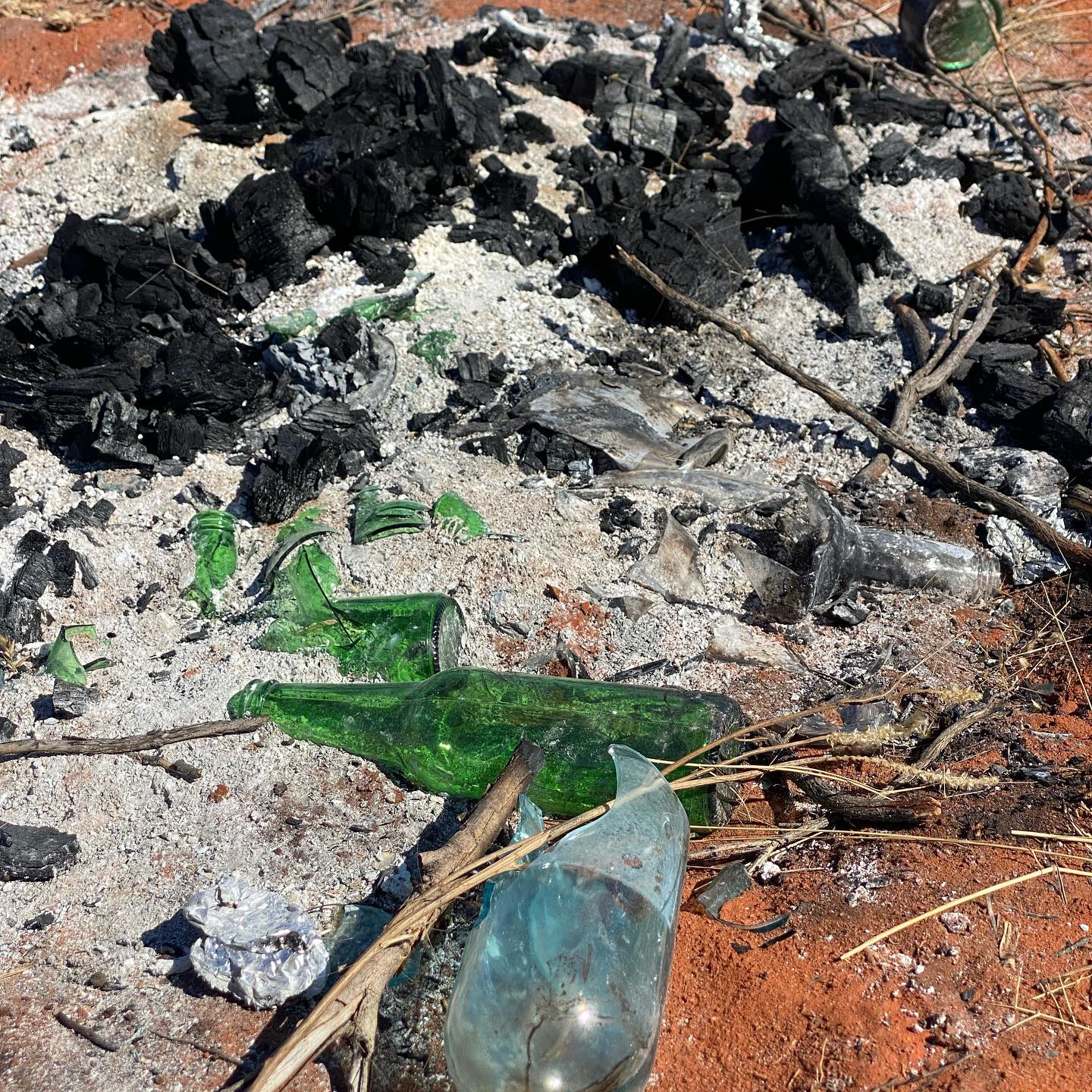 Broken glass on the ashes of an old campfire.