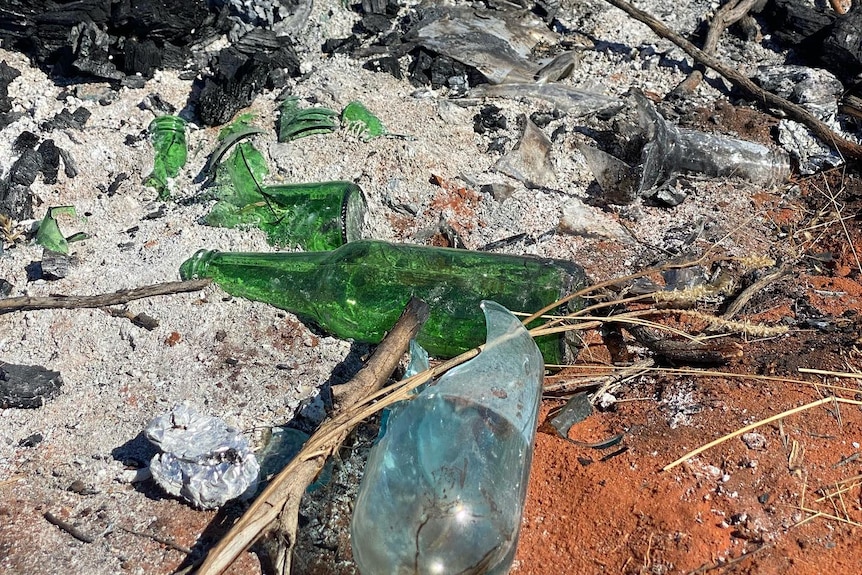 Broken glass on the ashes of an old campfire.