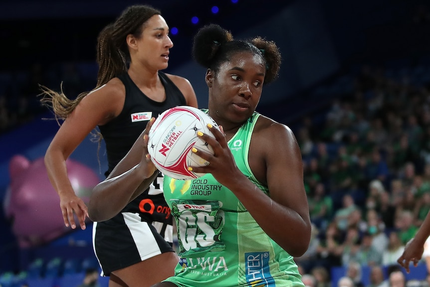 A West Coast Fever Super Netball player holds the ball against Collingwood Magpies.