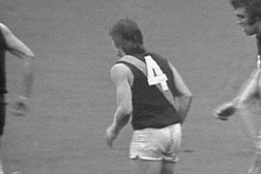 A black and white photo of a man wearing a Richmond jumper with the number 4 on his back.